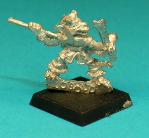 Pose 3, variant D. This figure holds 2 javelins in his left hand, and is about to launch a third one with his right. He wears a cap with long ear-flaps and has 2 backwards-curving horns, large, pointed ears and a grinning mouth.