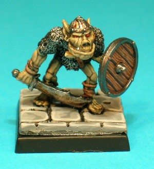 Pose 2, variant A. This is the sword wielding pose. He wears a tattered chainmail shirt and carries a curved scimitar in his right hand, with the only variant details being in the facial features and headgear. This one has a closed mouth with small protruding lower fangs, and he wears a plain steel skullcap with a single reinforcing band and small rivets.